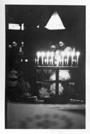 Else and Paul Blum in front of a brightly lit Hanukkah menorah