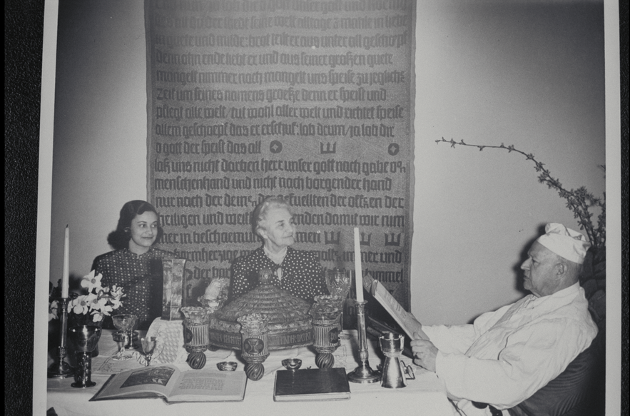 Guggenheim family seated around the table and reading the Haggadah during the Passover Seder (1953).