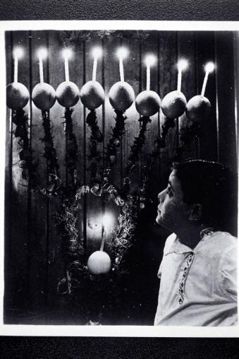 A child in front of a Hanukkah lamp made of oranges.